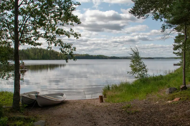 Kaksi valkoista soutuvenettä järven rannalla kesäpäivänä.
